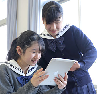 iPadの画面をのぞき込む生徒二人。